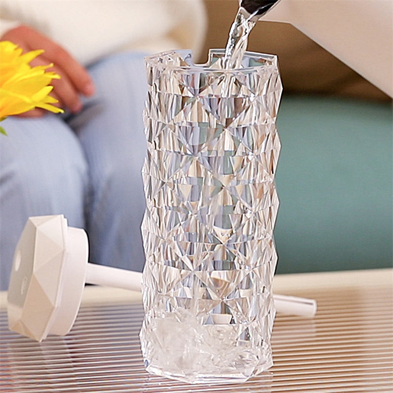 Elegant Air Humidifier Crystal Lamp emitting a soothing mist to improve air quality, paired with a warm, ambient light that glows through its crystal-like structure. The lamp is displayed on a wooden surface, highlighting its modern design and dual functionality as both a humidifier and a decorative lamp.