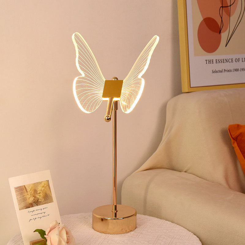 Charming Fairy Table Lamp featuring a delicate design with fairy silhouette cutouts, casting a warm and whimsical pattern of light and shadows when illuminated. The lamp is displayed on a wooden table, enhancing its magical and enchanting appeal.